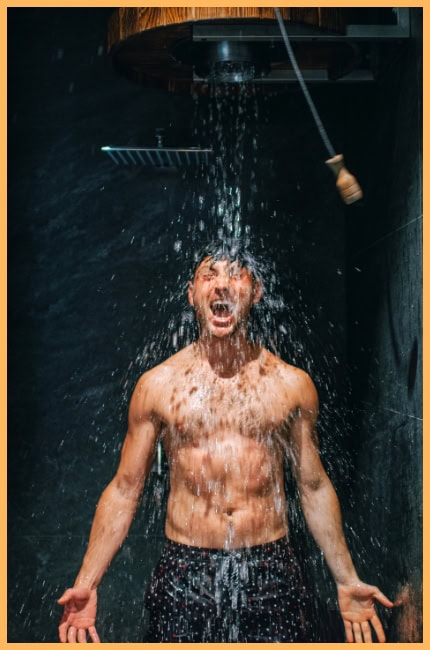 A powerful image of a shirtless man standing under a cold shower, water cascading over his body as he screams with raw emotion. The dark, minimalistic bathroom setting emphasizes resilience, discomfort, and the mental toughness required to embrace challenges.