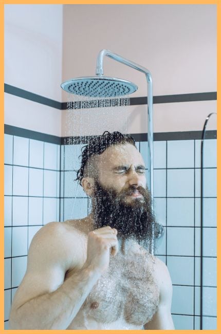 Man showing an expression of discomfort from cold water in the shower