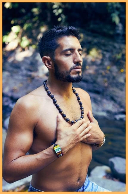 man with hands on chest and eyes close performing breathing exercise in the early morning